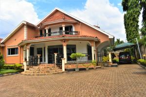 a house with a balcony on a brick driveway at Beautiful home opposite Speke Resort Munyonyo near Lake Victoria in Kampala