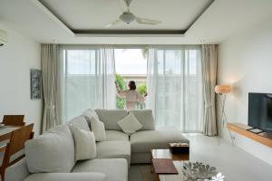 a woman is looking out the window of a living room at Chi Samui Resort in Bophut