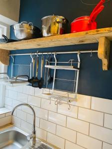 a kitchen with a sink and a shelf with pots and pans at Old Fisherman Nest in Old Town in Hastings