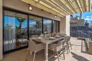 Une table à manger et des chaises sont disponibles sur la terrasse. dans l'établissement Tajinaste villa, à Adeje