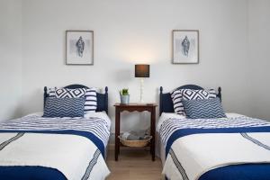 a bedroom with two beds with blue and white sheets at Portsea - Sea Views Close to Beach in Saundersfoot