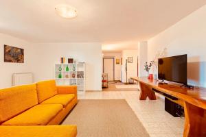 een woonkamer met een gele bank en een televisie bij Spacious new 2 bdr walk-out apartment in Fara Novarese