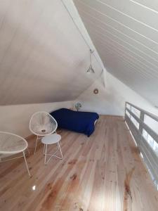 a attic room with a bed and two chairs at La maison du Lac in Doussard