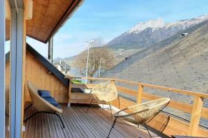 a balcony with chairs and a table and mountains at La maison du Lac in Doussard