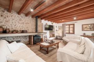 a living room with white furniture and a stone wall at Villa Agnes in Pollença