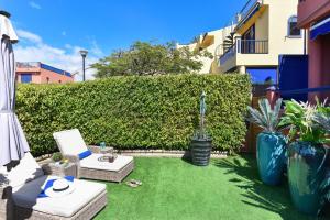 a small backyard with grass and a hedge at Bahia Meloneras MJV96 by VillaGranCanaria in Meloneras