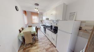a kitchen with a table and a white refrigerator at Harmony Apartment VRT in Şelimbăr