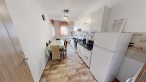 a kitchen with a white refrigerator and a table at Harmony Apartment VRT in Şelimbăr +4 photos