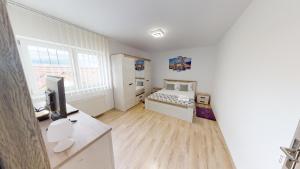 a white room with a bed and a television at Harmony Apartment VRT in Şelimbăr