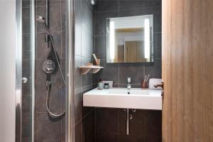a bathroom with a sink and a shower with a mirror at Résidence Pierre & Vacances Premium Les Chalets du Forum in Courchevel +54 photos