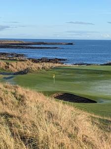 a golf course with the ocean in the background at Balloan Steading West in Dornoch