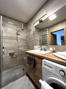 a bathroom with a shower and a sink and a washing machine at Apartament na Rydlówce in Krakow