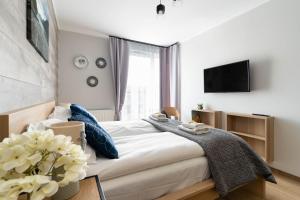 a bedroom with a bed with a tv on the wall at INA Rent - Przystań Letnica in Gdańsk