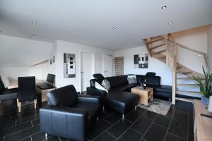 una sala de estar con muebles negros y una escalera. en Weingut Heinen, en Longuich
