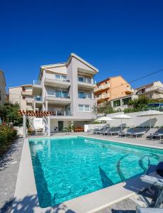 a swimming pool in front of a building at Azalea Apartments in Podstrana