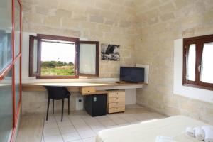 a room with a desk and a television in a room at Hotel Delle Cave in Favignana