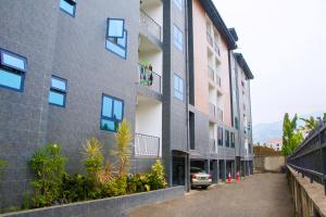 un edificio de apartamentos con un coche aparcado al lado en Candide Guest House, en Limbe