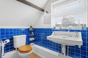 uma casa de banho em azulejos azuis com um WC e um lavatório em The Corner House, 36, Broadway Road, em Evesham