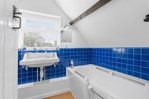 uma casa de banho em azulejos azuis com uma banheira e um lavatório em The Corner House, 36, Broadway Road, em Evesham