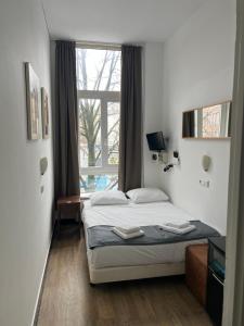 a bedroom with a bed and a large window at MAX Hotel Amsterdam in Amsterdam