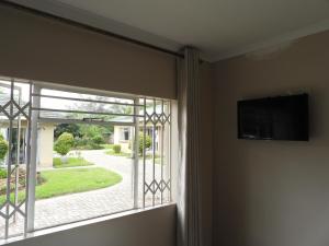 een kamer met een raam en een flatscreen-tv bij 2 bedroomed apartment with en-suite and kitchenette - 2064 in Harare
