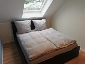 Bett mit weißer Bettwäsche und Kissen unter einem Fenster in der Unterkunft FeWo Wiardergroden - Horumersiel in Horumersiel