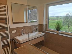 ein Bad mit einem Waschbecken und einem Fenster in der Unterkunft FeWo Wiardergroden - Horumersiel in Horumersiel