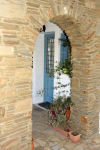an archway leading into a white house with a blue door at Andros Guesthouses in Andros