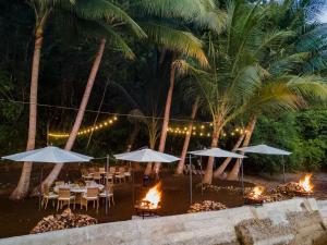 un restaurante con mesas, sombrillas y chimeneas en Kunken Boutique Hotel & Spa, en Puerto Jiménez