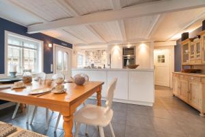 a kitchen with a wooden table and white cabinets at Friesenhof Feer in Oldsum
