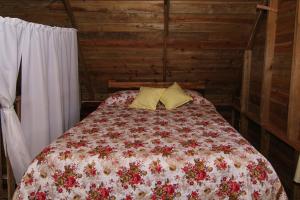 a bedroom with a bed with a floral blanket and two pillows at Pilgrims Paradise Cabin 2 in San Ignacio