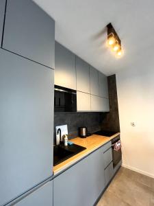 Apartament na Rydlówce في كراكوف: مطبخ مع دواليب بيضاء ومغسلة