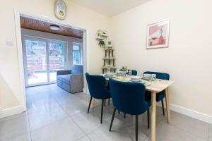 a dining room with a table and blue chairs at Beautiful 3 bedroom house, Ashbnhm,Luton free parking in Luton