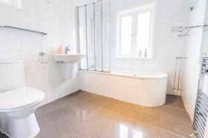 a white bathroom with a sink and a tub and a toilet at Beautiful 3 bedroom house, Ashbnhm,Luton free parking in Luton