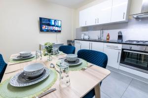 a kitchen with a wooden table with blue chairs at 3 bedroom House for Contractors,Workers,Relocation,Insurance,Family, Free Parking, Ashburnham 1 in Luton +2 photos