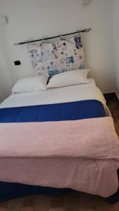 een bed met blauwe en witte lakens en kussens bij Lighthouse Taranto in Taranto