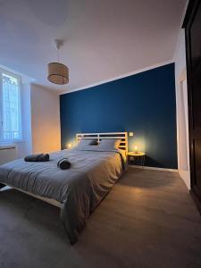 une chambre avec un grand lit avec un mur bleu dans l'établissement Les Vans - Charmant appartement au cœur du village, aux Vans