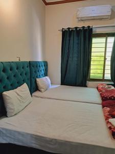 Lords Hotel في لاهور: غرفة نوم بسريرين و اللوح الأمامي الأزرق