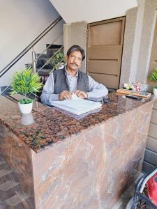 un homme assis à un comptoir écrivant sur un papier dans l'établissement Lords Hotel, à Lahore