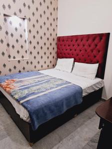 Lords Hotel في لاهور: غرفة نوم مع سرير مع اللوح الأمامي الأحمر