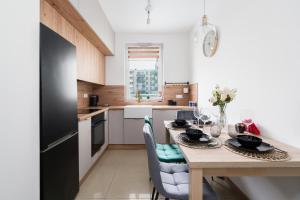 uma cozinha com uma mesa com cadeiras e um frigorífico preto em Arena Lux Apartment Kasprowicz Park by Renters Prestige em Poznań