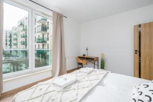 um quarto com uma cama e uma grande janela em Arena Lux Apartment Kasprowicz Park by Renters Prestige em Poznań