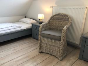 um quarto com uma cadeira de vime ao lado de uma cama em Glebbe 66 _ Hus Suennschien em Zingst