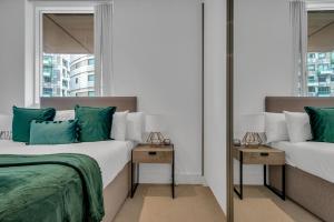 a bedroom with two beds with green and white pillows at Modern 01 & 02 Bed Apartment in Canary Wharf in London