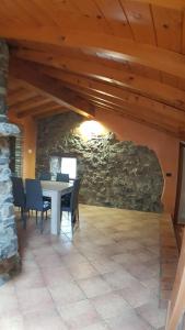 a dining room with a table and chairs and a stone wall at CASA VAL DEL RISO in Gorno