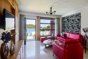 un soggiorno con mobili rossi e vista sull'acqua di Villa Andriana Karvouno Villas a Sivota