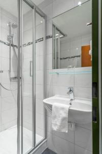 uma casa de banho branca com um lavatório e um chuveiro em BSW Hotel Hubertus-Park em Schönau am Königssee