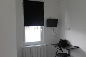 Zimmer mit einem Fenster mit einem schwarzen Vorhang und einem Stuhl in der Unterkunft Hôtel et Restaurant de la Gare Torigny-les-Villes in Torigni-sur-Vire