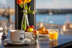 a table with a plate of food and a cup of orange juice at Hotel Atlantique in Le Palais