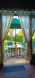 a picnic table with a green umbrella and two chairs at Villa Pintu Bintang in Pawenang